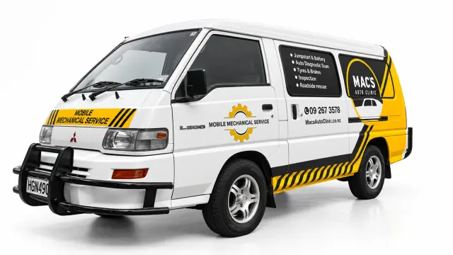 Front-quarter view of a white Mac’s Auto Clinic van with yellow-and-black mobile-mechanic graphics.